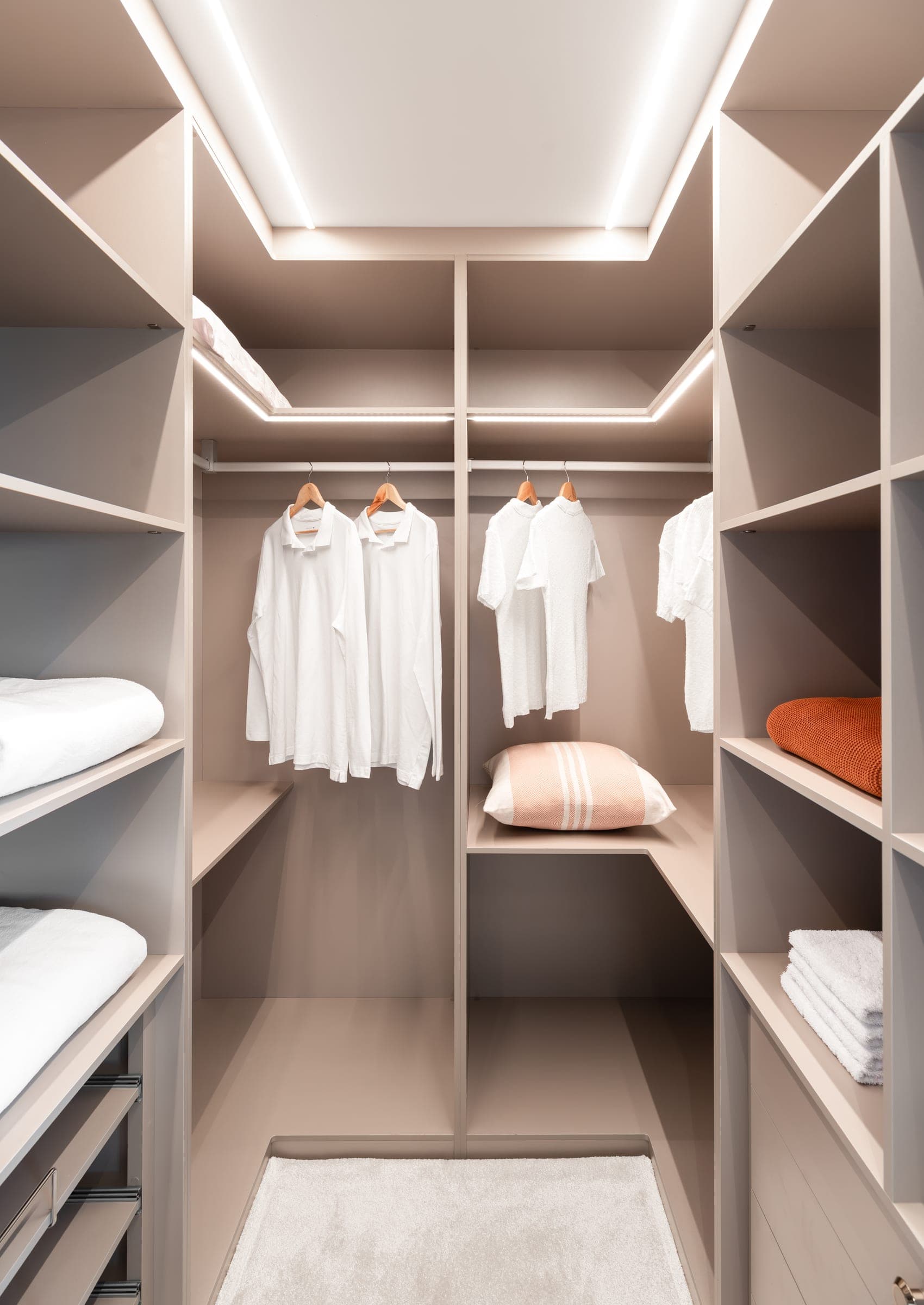 Closet em U em laca taupe com cabideiros, prateleiras e sanca iluminada