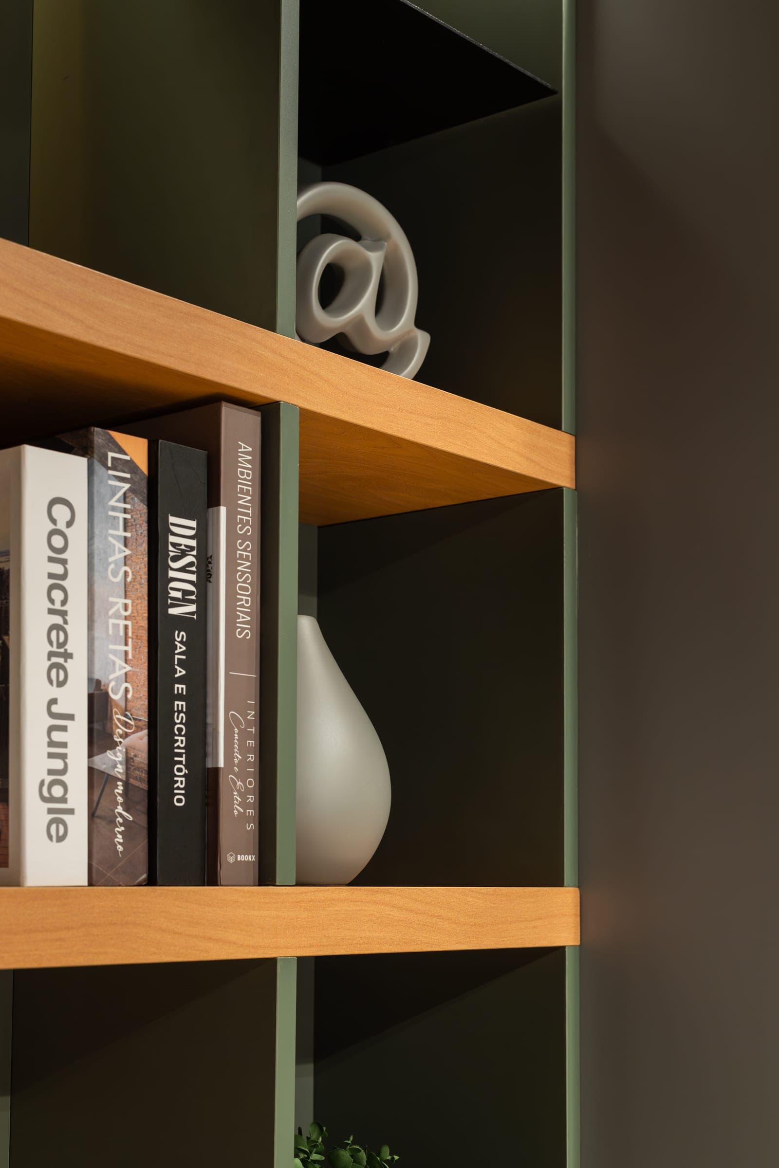 Estante com nichos em laca verde-oliva e prateleiras em madeira com livros