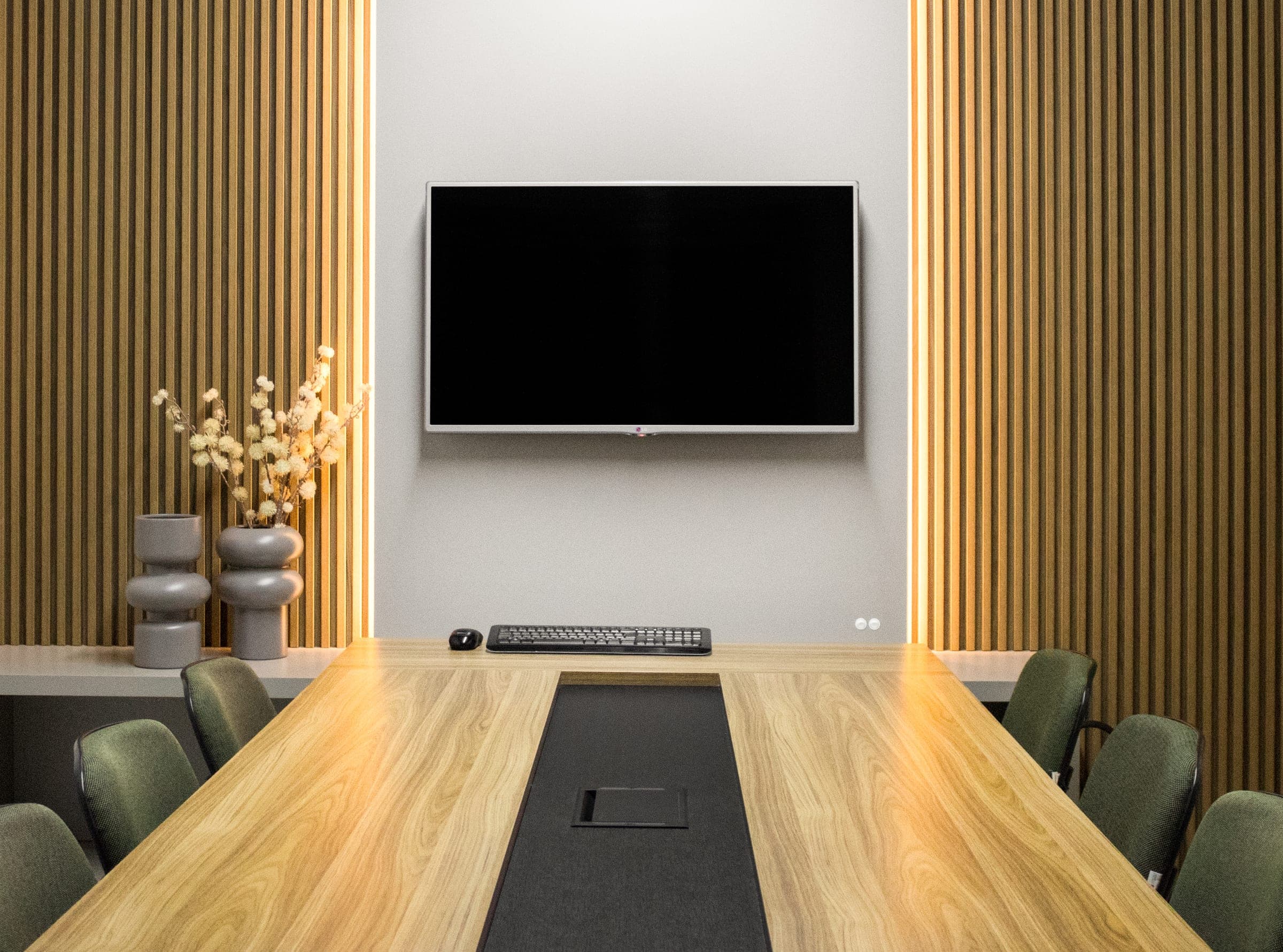 Sala de reunião com mesa longa em madeira e ripados iluminados nas laterais