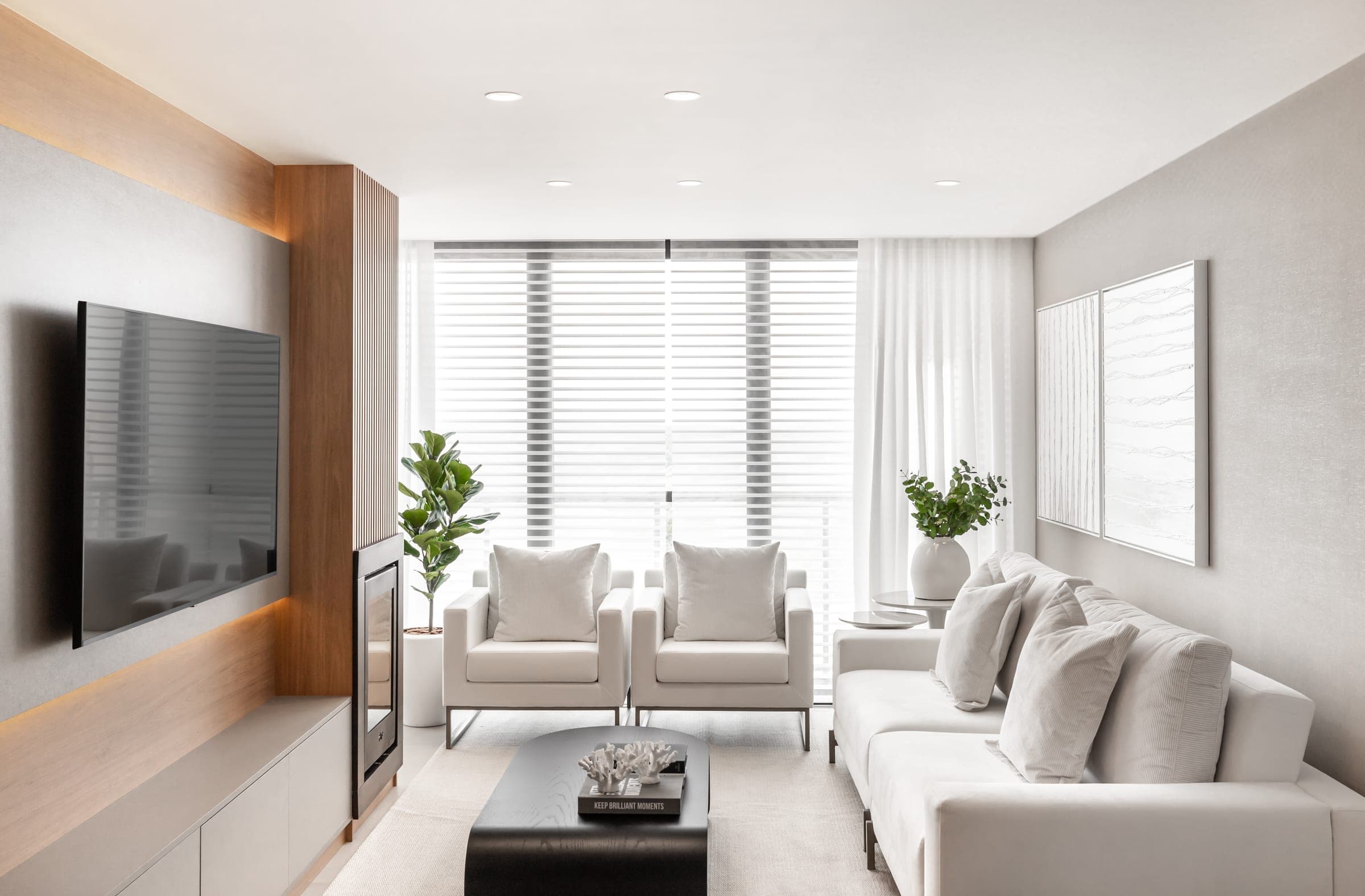 Living claro com poltronas brancas, sofá e painel de TV emoldurado em carvalho