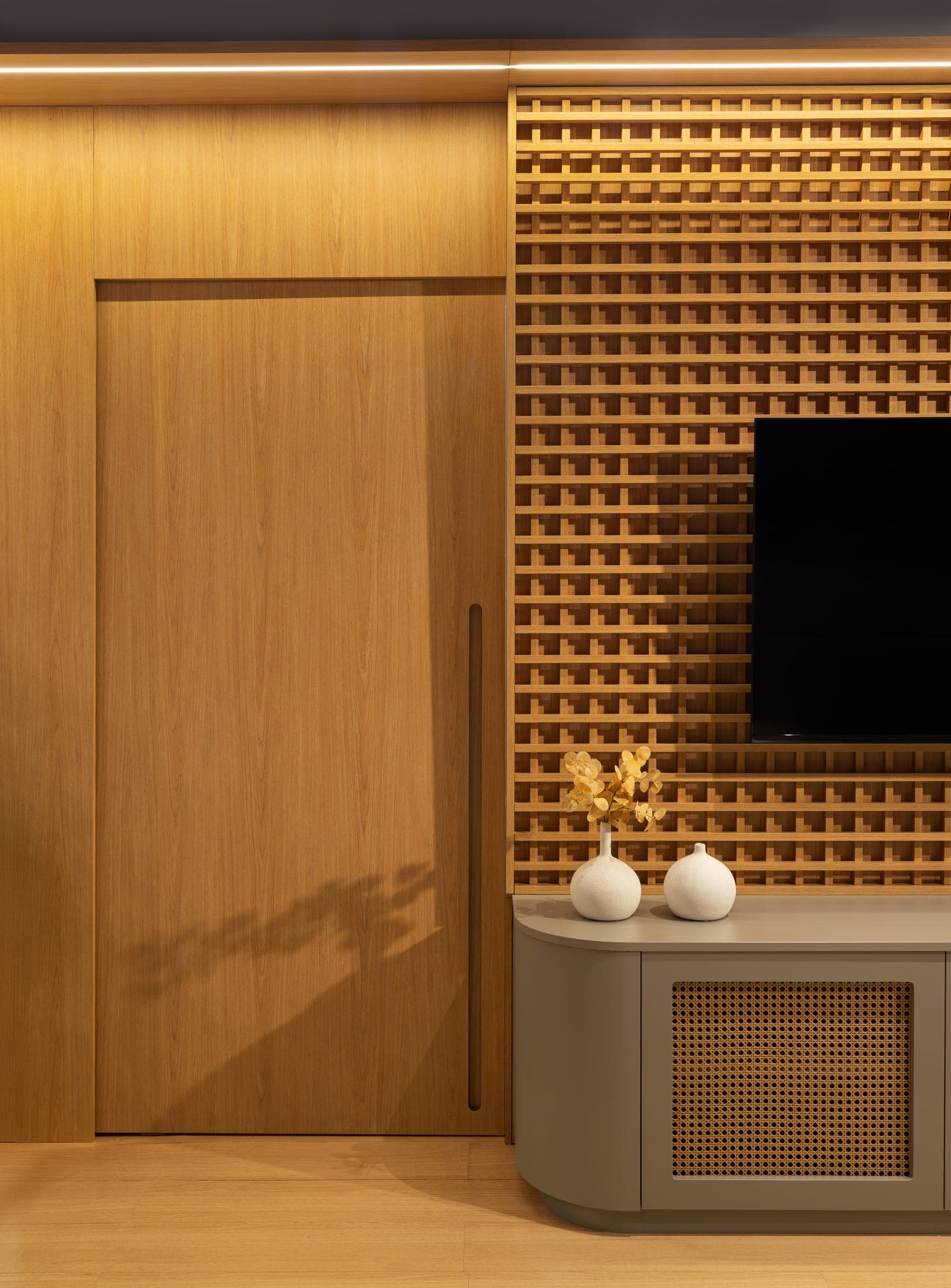 Painel muxarabi em freijó com TV e porta invisível em lâmina de madeira